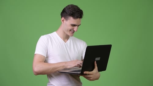Young Adult Typing on Laptop with Green Screen