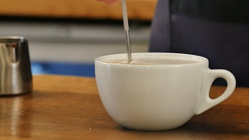 Barista Stirring Hot Coffee in White Cup