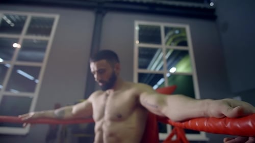 Muscular Heavyweight Boxer Resting in the Corner of the Ring Leaning Back on the Ropes