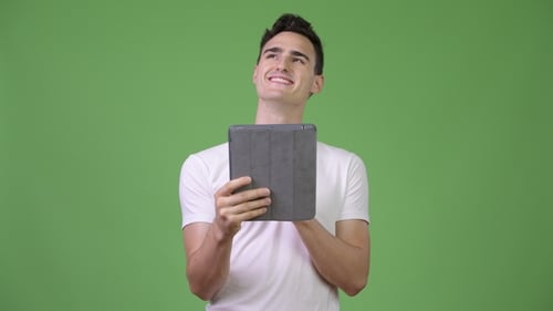 Young Man Uses Tablet, Smiling and Thinking