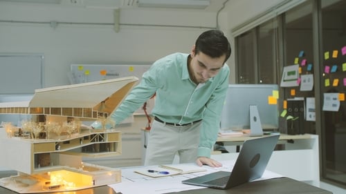 Male Architect Working on an Architectural Model in the Office at Night