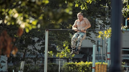 Jeune athlète fait un pull-up sur la barre transversale de la puissance de sortie sur le terrain de sport