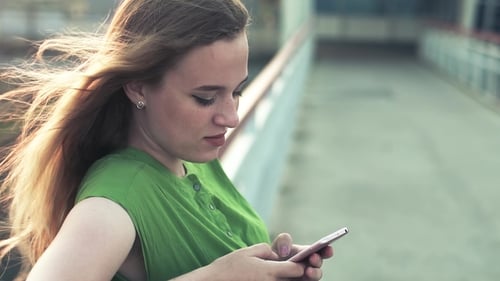 a Young Girl in the City with a Smartphone Reads Message Green Dress