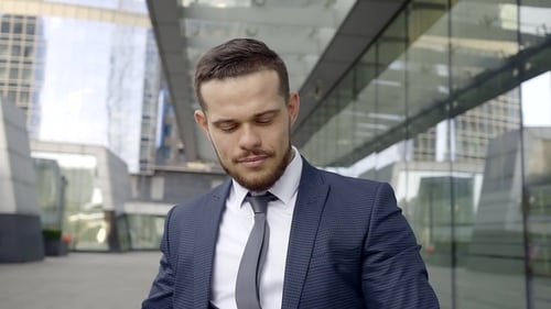 Handsome Young Businessman with Cup of Coffee in a Hand, Looking on a Watch, Standing on a Street