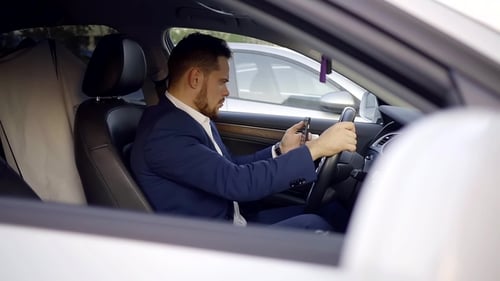 Man in Suit Using Smartphone in Car