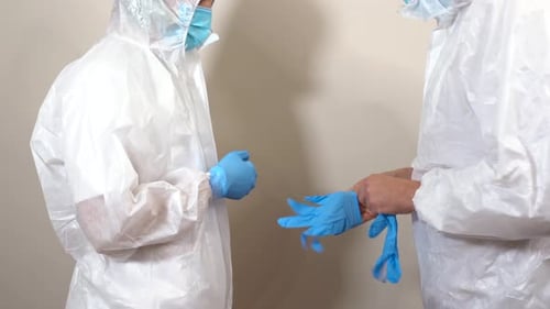 Medical Professionals Putting on Gowns and Surgical Gloves