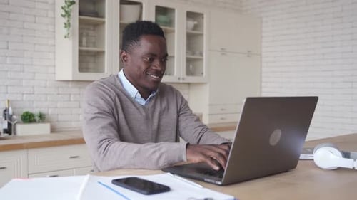 Smiling African American Man Using Laptop Computer Working From Home Office