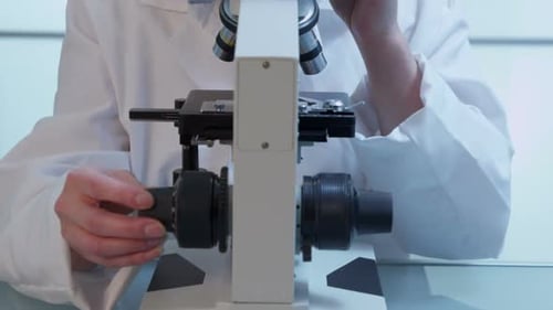 Female Scientist Using Microscope in Bright Lab