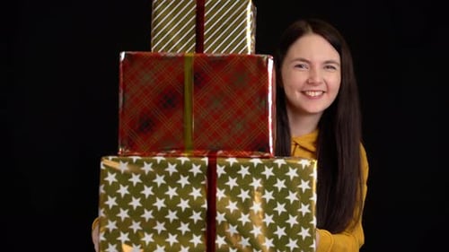 Young Woman Holding Stack of Christmas Gifts