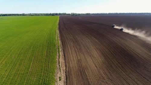 Aerial View of Agricultural Tractors Cultivating Field.