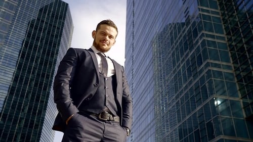 Portrait of Young, Confident and Strong Businessman Standing and Checking the Time with Skyscrapers