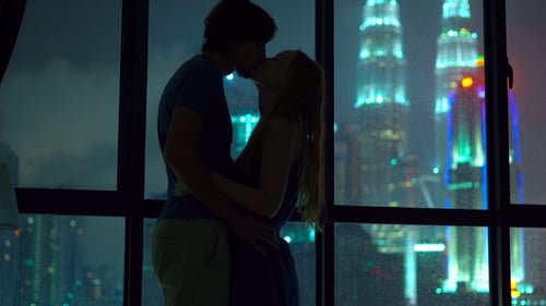 Romantic Couple Kissing Silhouetted Against City Lights