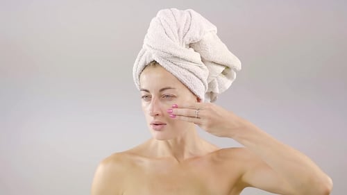 Hübsches Mädchen mit guter Haut befasst sich mit drei Finger weißer Creme im Gesicht. das Verfahren für