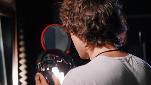 Young Handsome Singer Man Puts on Headphones in the Studio. Recording New Melody or Album. Male