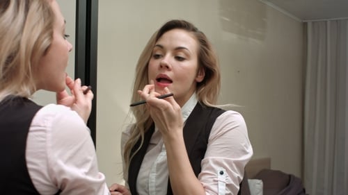 Woman Applies Makeup in the Mirror