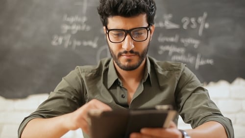 Man Using Tablet in Front of Chalkboard