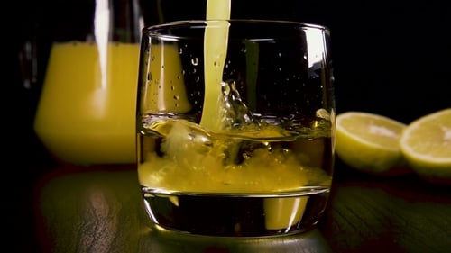 Pouring Refreshing Yellow Beverage Into Clear Glass