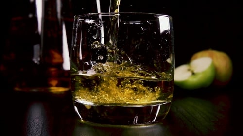 Pouring Yellow Liquid into Glass with Apples