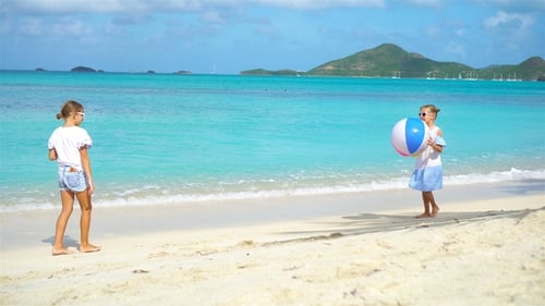 Adorables petites filles jouant avec le ballon sur la plage