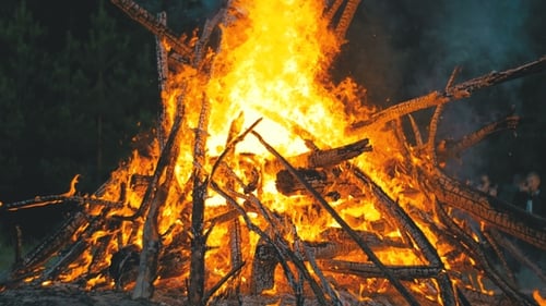Großes Lagerfeuer aus Ästen brennt nachts im Wald