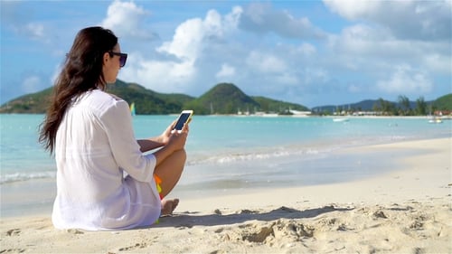 Woman Using Phone on Beach on Sunny Day