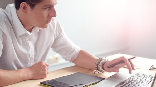 Young Adult Designer Working at Desk with Laptop