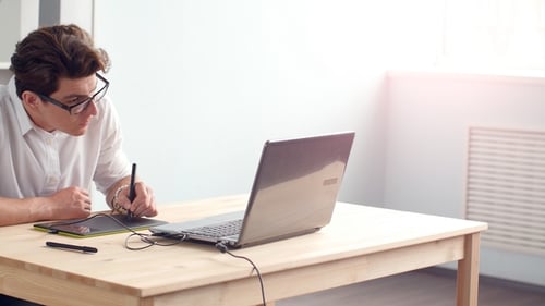 Man Uses Graphic Tablet and Laptop
