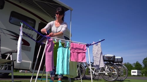 Woman Hanging Laundry at Campsite on Sunny Day
