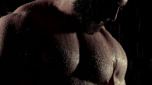 Naked Chest of Young Man with Inflated Muscles, Water Is Dropping From His Body in Darkness