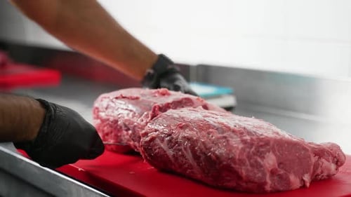 Chef cuts raw beef steak on cutting board