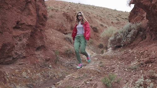 Touristin in Sonnenbrille geht auf ein ungewöhnliches Terrain, rote Berge und rote Erde wie auf dem Mars
