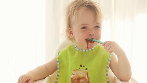 Happy Toddler Eating Messy Food in High Chair