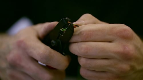 Man Stripping Coating off Electrical Wires with Tool
