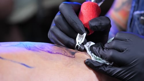Tattoo Artist Demonstrates Process of Getting Black Tattoo with Paint and Machine. Woman Works in
