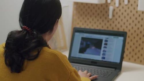 Young Adult Typing on Laptop at Desk Indoors