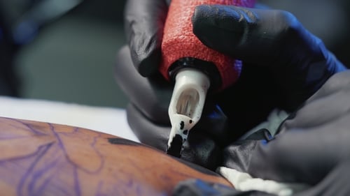 Tätowierer demonstriert den Prozess des schwarzen Tattoos mit Farbe und Maschine. Frau arbeitet in