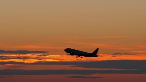 Silhouette noire d'avion volant contre le ciel du soir doré