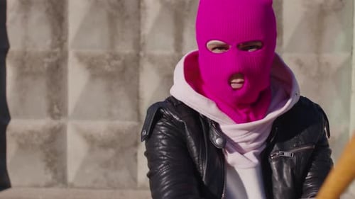 Junge Frau in rosa Sturmhaube mit Baseballschläger in den Händen