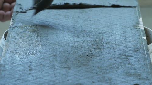 Adhesive Spreads on Gray Tile with a Toothed Tool