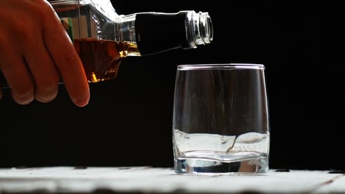 Whiskey Pouring into a Glass on White Table