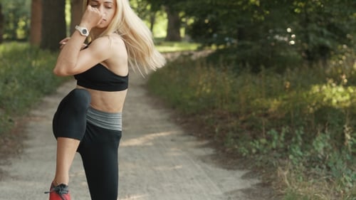 Young Woman Warming Up Before Jogging in Park