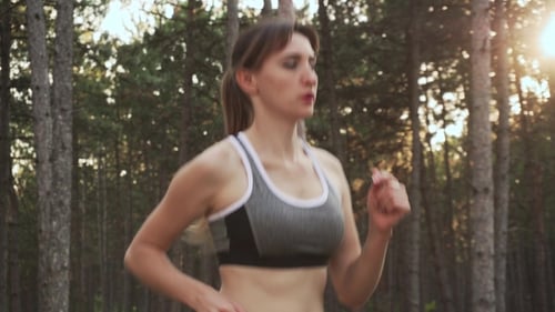 Sweaty Athletic Woman Running Through Woods in Athletic Clothes