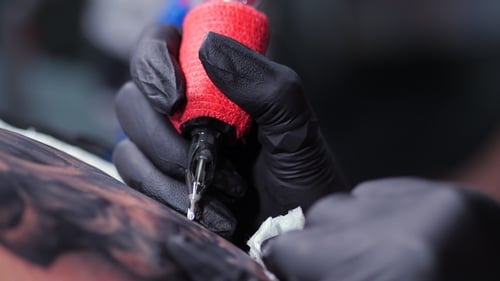 Professional Master Is Painting Tattoo with Black Ink