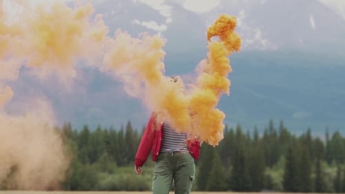 Woman Holding Smoke Grenade with Mountains in Background