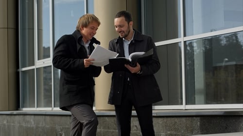 Men Discussing Work Documents Outside Office Building