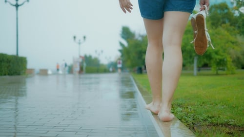 Girl Walking in the Park on the Curb Barefoot in the Rain