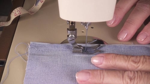 Les mains des femmes cousent le tissu sur la machine à coudre