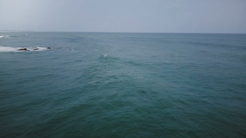 Drone Camera Turning Left Following Big Ocean Wave Reaching the Coast, Foaming and Crashing on a