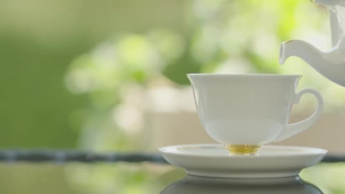 Tea Pouring From Teapot into Cup on Saucer
