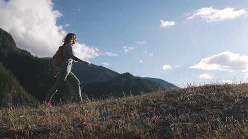 Woman Hiker Walks Across Hilltop in Mountain Landscape
